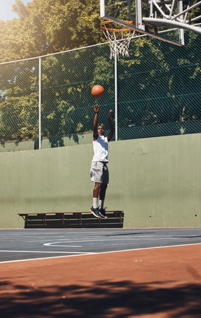 Basketball, jump and athlete scoring a goal during a match or training on an outdoor court. Fitness,...