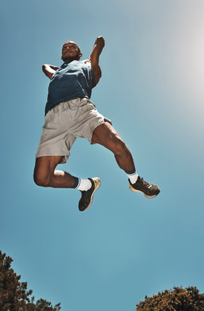 Sports, blue sky and basketball man jump for game, competition or slam dunk training, practice or workout. High energy, athlete motivation and basketball player doing fitness or exercise bottom viewの写真素材