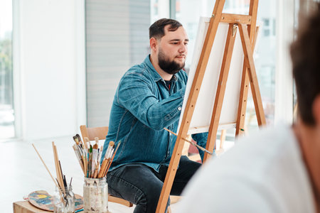 I can be creative through art. a handsome young artist sitting and painting during an art class in the studio.の写真素材