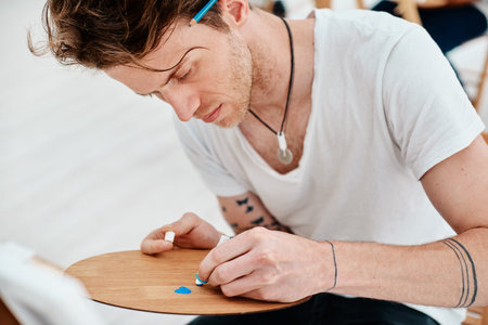 Art is what you make others see. a handsome young artist squeezing paint onto a palette during an...