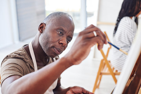 Exercising our creativity gives us an outlet from our daily routines. a middle aged man painting in a art studio.の写真素材