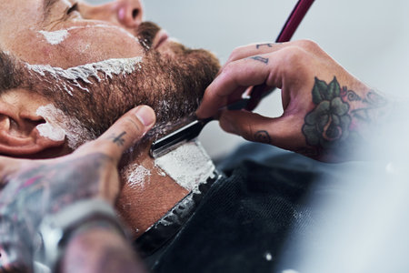 To beard or not to beard. an unrecognizable man getting his beard trimmed and lined up at a barbershop.の写真素材