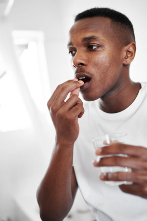 This will give me the boost I need. a young man taking medication at home.