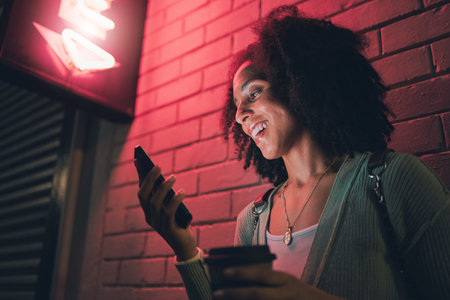 Black woman, phone and night in city with smile on social media, app or communication on travel,...