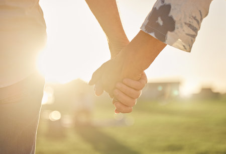 Retirement, couple and hands with sun closeup of married man and woman on field for summer walk. Support, care and trust of senior people in marriage walking in sunlight for romantic evening.の写真素材