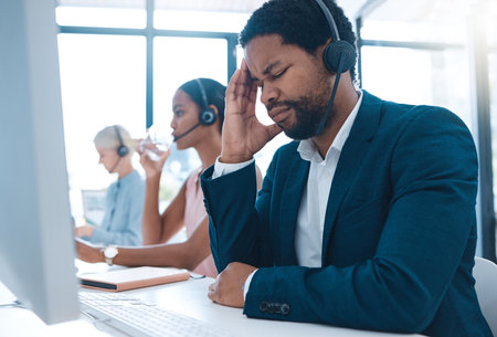 Stress, headache and call center businessman on computer for customer service or consulting. Support agent, black man and telemarketing virtual advisor tired, frustrated or burnout at crm officeの写真素材