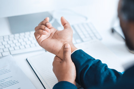 Hands of business man with pain, carpal tunnel syndrome or strain from corporate job, working or typing on keyboard. Arthritis risk, hurt and wrist of black man or office employee with injury problemの写真素材