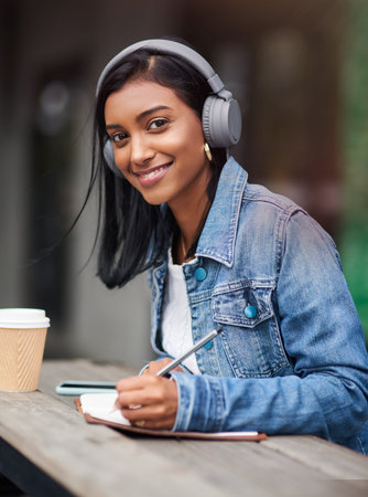 No one ever regrets studying. a young woman making notes while sitting outdoors.