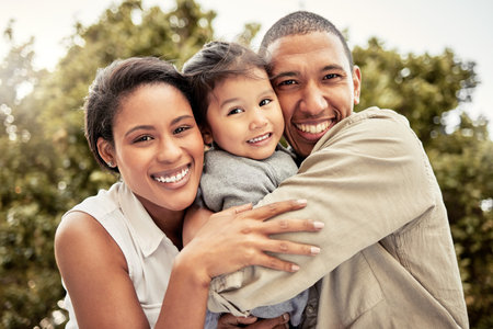 Hug, child and parents with smile in a park for love, care and adventure on a holiday in Maldives. Happy, travel and portrait of mother and father hugging kid while on vacation in a nature gardenの写真素材