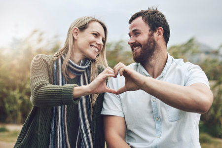 Couple, hands and smile with love gesture for happy relationship bonding and care in the outdoors....