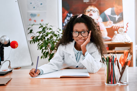 Smart is the new cool kids. Portrait of an adorable young school girl writing notes in her note book in science class at school.の写真素材
