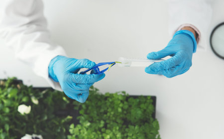 Phytology is a fascinating study. an unrecognizable female scientist using a tweezer to put a plant...