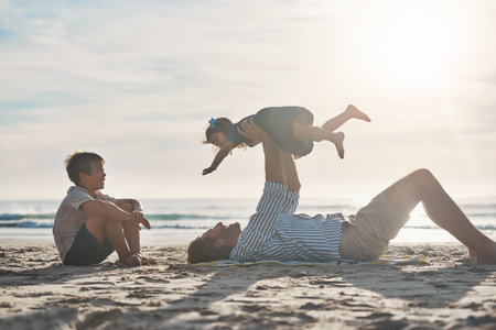 My children have been a blessing from the start. an affectionate mature father bonding with his two children during a day on the beach together.の写真素材