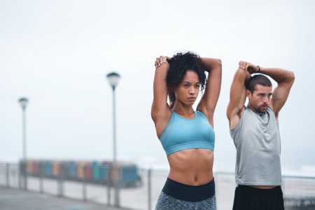 Focused on getting their bodies loose and limber. two sporty young people stretching while exercising outdoors.の写真素材