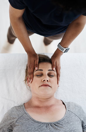 Let her healing hands relieve all your pain and tension. a mature woman getting her head and neck treated by a physiotherapist at a clinic.の写真素材