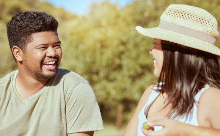 Happy, love and couple in nature in a conversation while on an outdoor garden picnic date in summer....