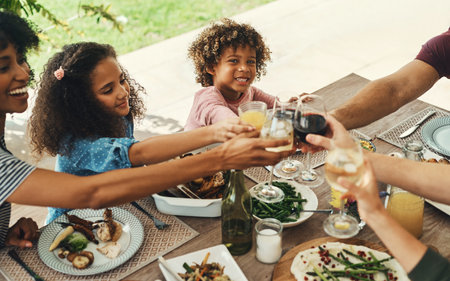 Celebrating with the ones who matter the most. beautiful young family raising their glasses for a toast during a family gathering at home.の写真素材