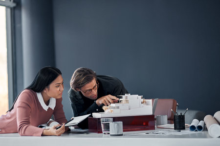 Ive made some slight adjustments over there. two young architects working together on a scale model of a modern house in their office.の写真素材