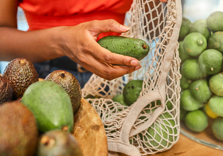 Hands, avocado and bag with a woman customer shopping in a grocery store for a health diet or...