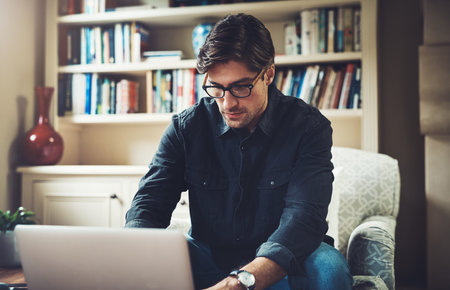 Your work ethic determines how far you go in business. a handsome young businessman working on a laptop in his office at home.の写真素材