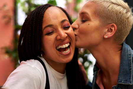 Her love and support means the world to me. an attractive young woman kissing her friend on the cheek while hanging out and having fun together outdoors.の写真素材