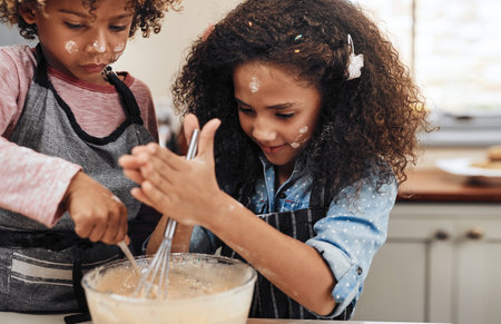 What better way to spoil mom than with cookies. a young boy and girl baking in the kitchen at home.の写真素材