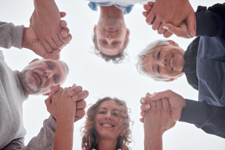 Family, below and holding hands in circle with smile, love and bonding together outdoor. Mom, dad and grandparents with support, unity and trust for care, happiness and help while happy on vacationの写真素材
