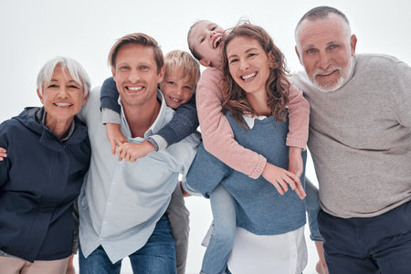 Happy big family, portrait and piggy back on holiday, vacation or trip against cloudy sky. Love, care and man, woman and children with grandparents bonding outdoors together in misty winter weather.の写真素材