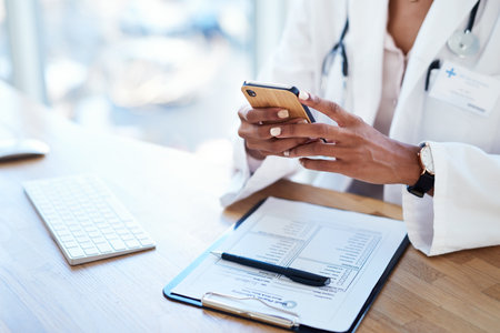 a doctor using a smartphone in her consulting room.の写真素材