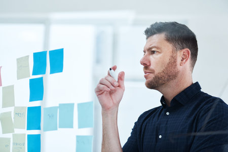 Careful planning always goes a long way. a handsome mature businessman working on a glass wipe board...