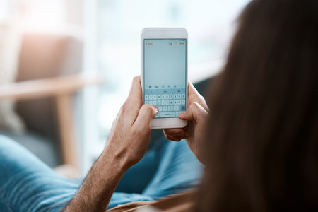Sharing my thoughts with the world. a young man using his cellphone while relaxing on a sofa in his...