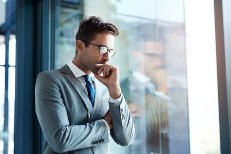 I have dreams and Im working to make them come true. a professional businessman looking thoughtful while standing in his office.の写真素材