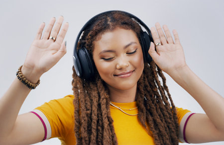 For the love of music. Studio shot of an attractive young woman dancing against a grey background.の写真素材