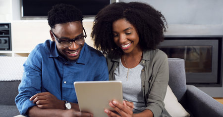 We definitely have to try that out. a cheerful young couple using a digital tablet together at home.の写真素材