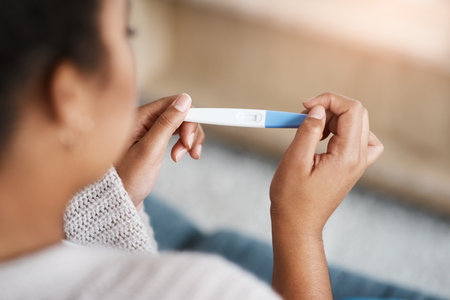 Here come the lines...an unrecognizable woman taking a pregnancy test at home.の写真素材