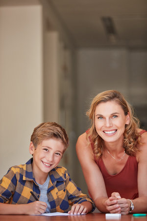As a parent, Im also an educator. a young woman helping her son with his homework at home.の写真素材
