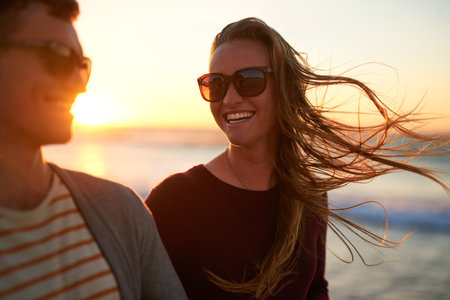 Shall I compare thee to a summers day. an affectionate young couple having a laugh together at the beach.の写真素材