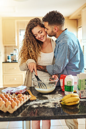 Our kitchen is filled with love. a loving couple baking in their kitchen.の写真素材