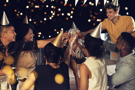 Lets all gather for a toast for the birthday girl. a group of friends raising their glasses up for a toast at a birthday celebration outdoors in the evening.の写真素材
