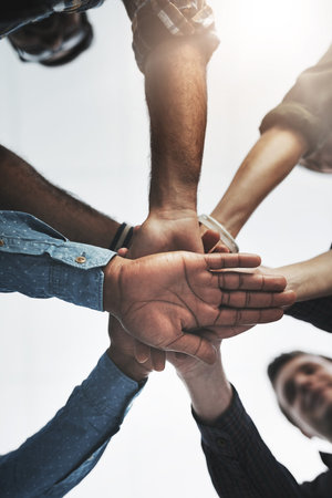 Together we can achieve anything. Low angle shot of a group of businesspeople holding hands together...