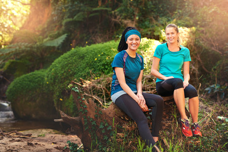 Youll never regret working out in nature. two sporty young women taking a break while out exercising in nature.の写真素材