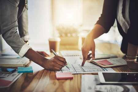 Laying all the details on the desk. Closeup shot of two businesswomen going through paperwork in an office.の写真素材
