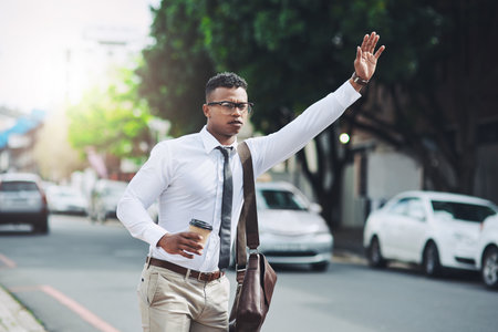 Making his way through to the office. a young businessman gesturing to get a cab in the city.の写真素材