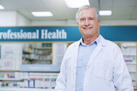 With decades of exceptional service, we are your best choice. Portrait of a senior male pharmacist smiling and posing in a pharmacy.の写真素材