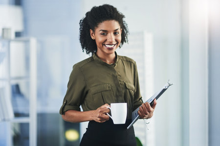 Always ready for new challenges. Portrait of a young businesswoman holding a cup of coffee and a...