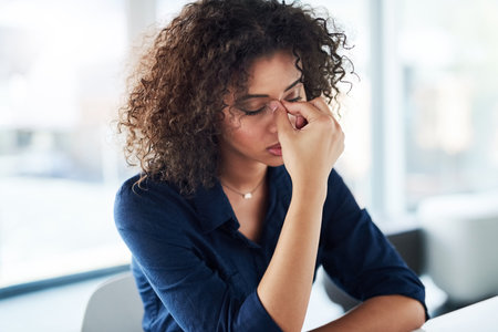 This job is becoming too stressful. an attractive young businesswoman looking stressed while working at her desk in the office.の写真素材