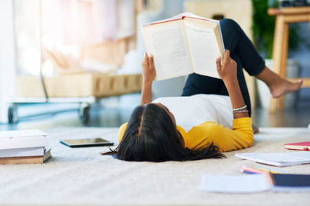 Studying and chilling at the same time. a young female student studying at home.の写真素材