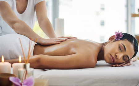 Stress busting back massage. an attractive young woman getting a massage at a spa.の写真素材