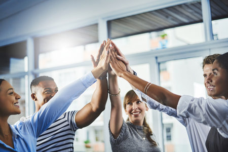 There is power in unity. Closeup shot of a group of businesspeople high fiving each other in an office.の写真素材