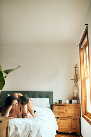 Romance is always worth waking up to. an affectionate young couple spending a romantic morning in bed at home.の写真素材